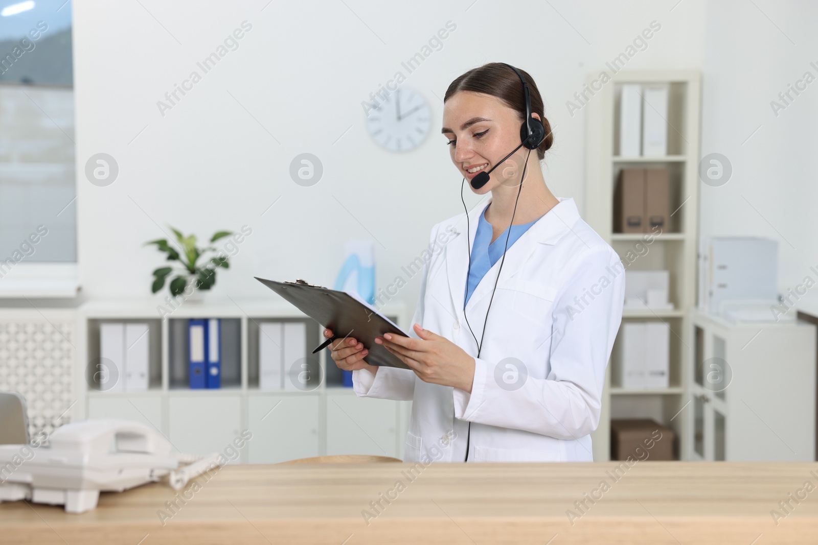 Photo of Professional receptionist working at wooden desk in hospital