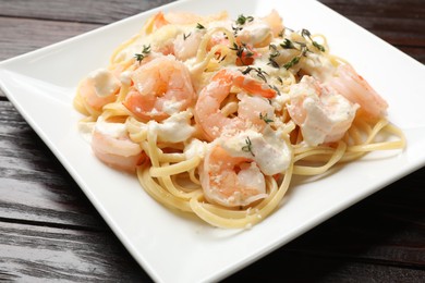 Photo of Delicious pasta with shrimps on wooden table, closeup