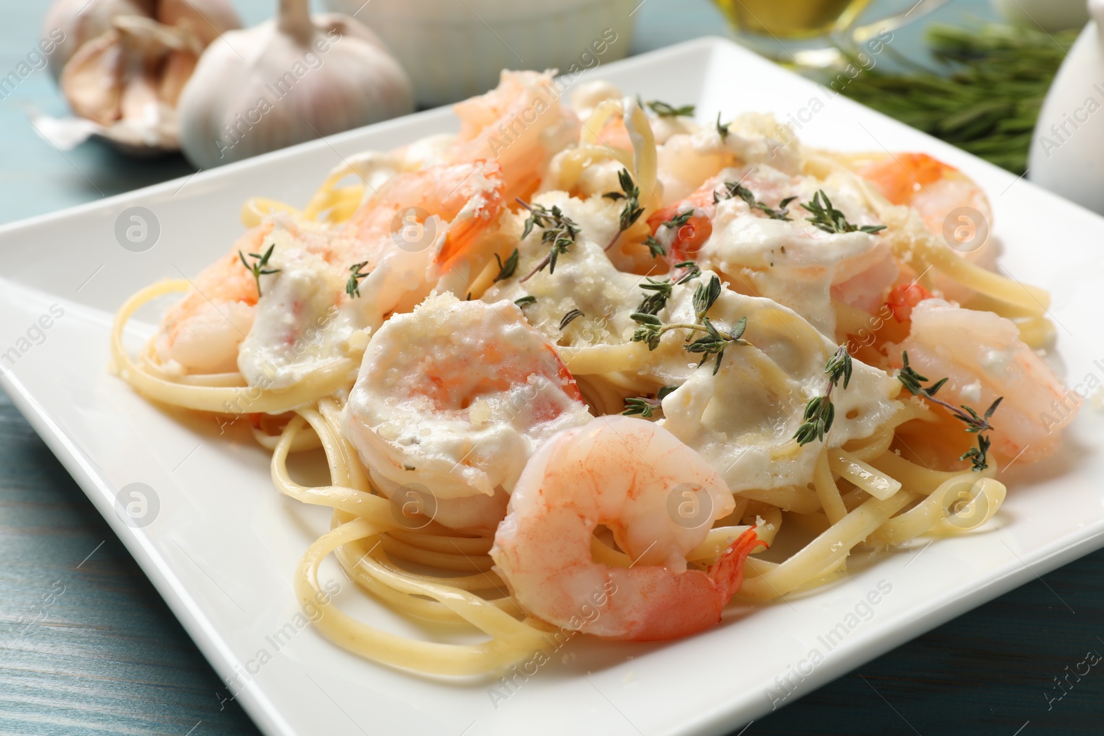 Photo of Delicious pasta with shrimps served on blue wooden table, closeup