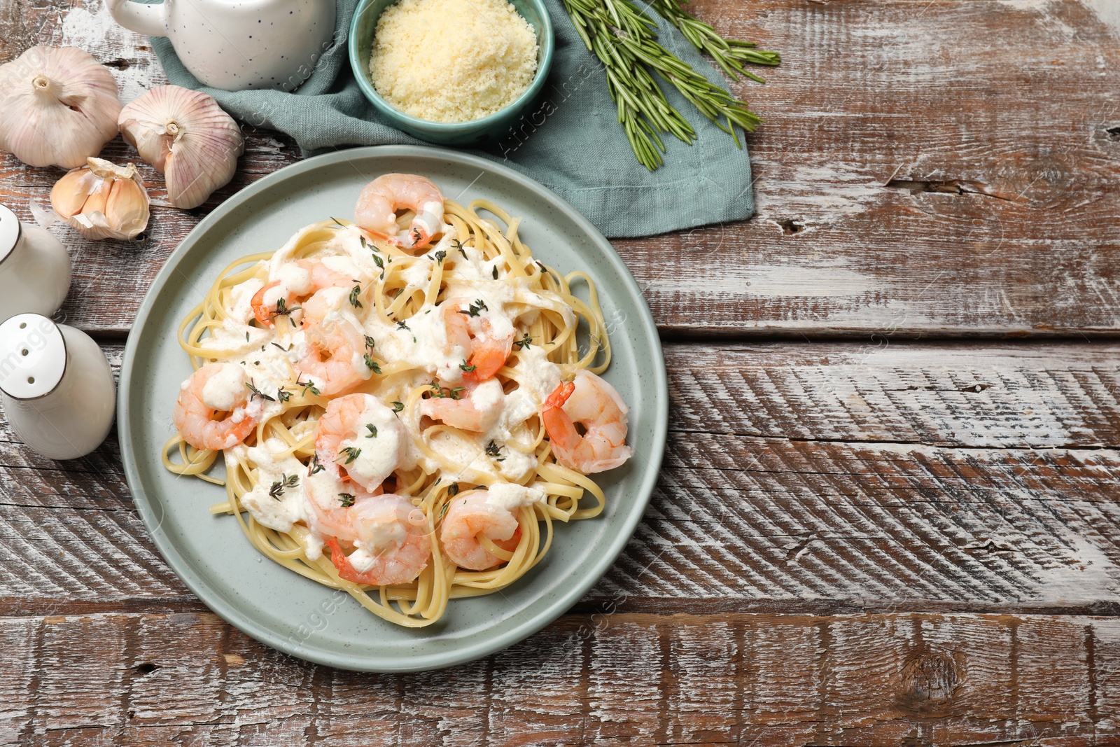 Photo of Delicious pasta with shrimps served on wooden table, flat lay. Space for text