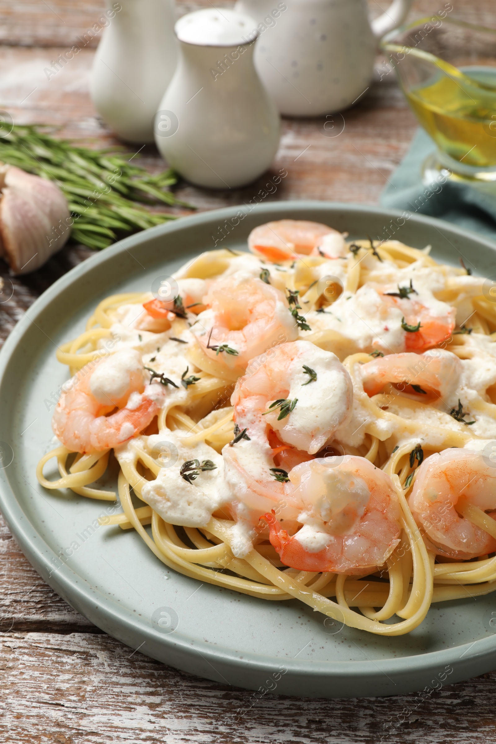 Photo of Delicious pasta with shrimps served on wooden table, closeup