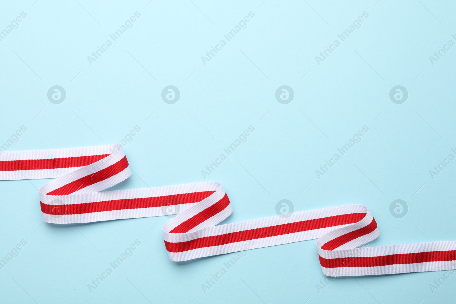 Photo of Striped ribbon on light blue background, top view. Space for text