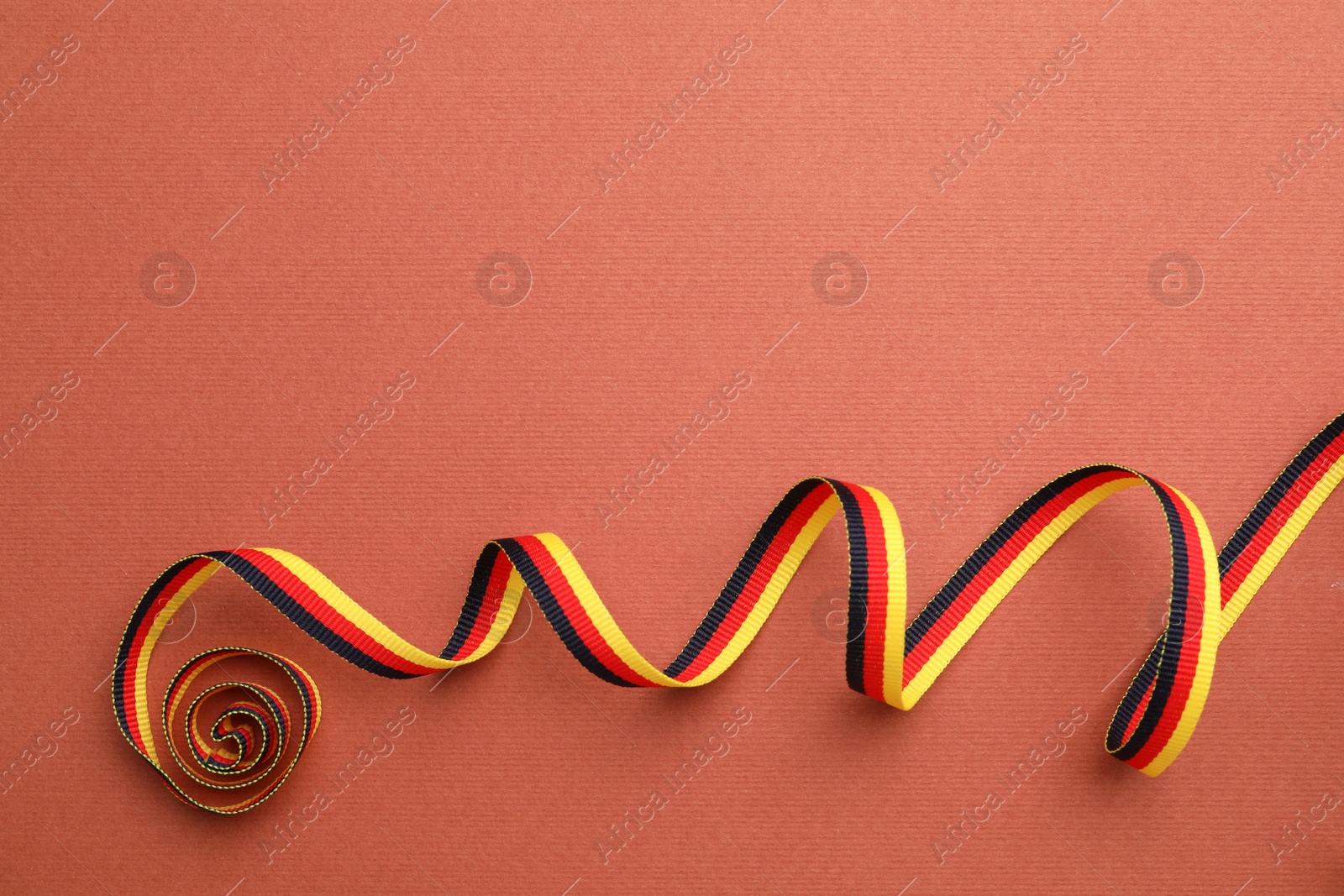 Photo of Ribbon in colors of German flag on color background, top view