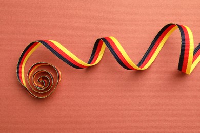 Ribbon in colors of German flag on color background, top view