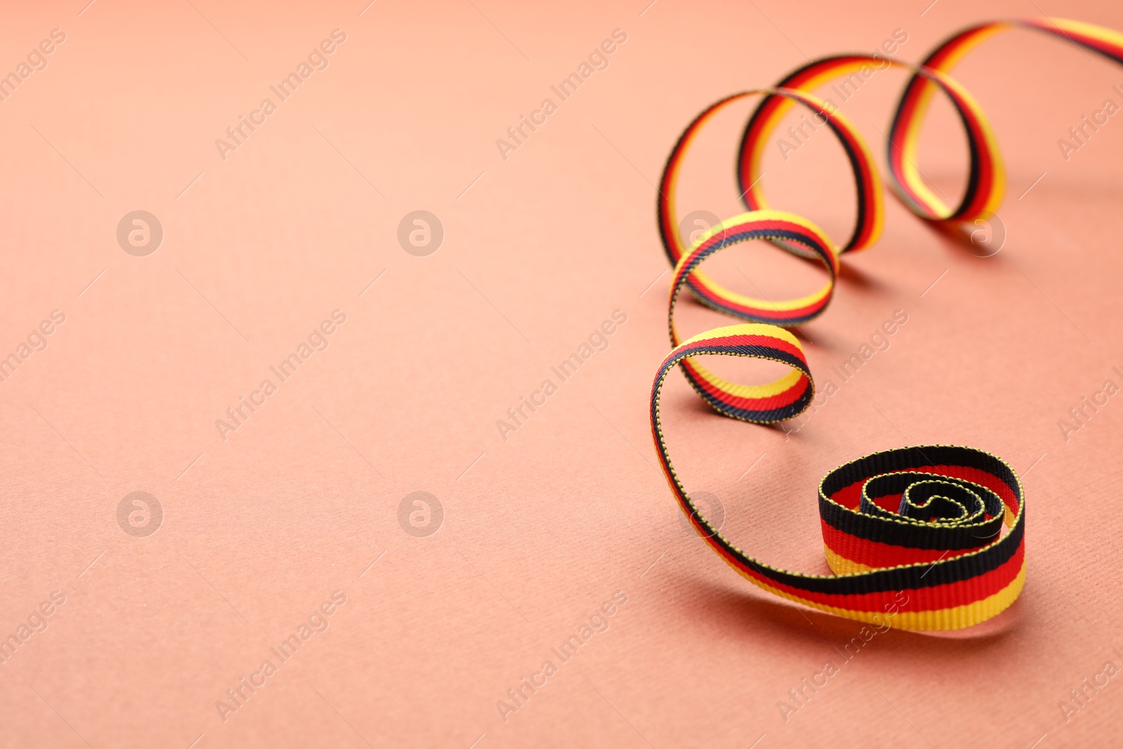 Photo of Ribbon in colors of German flag on color background. Space for text