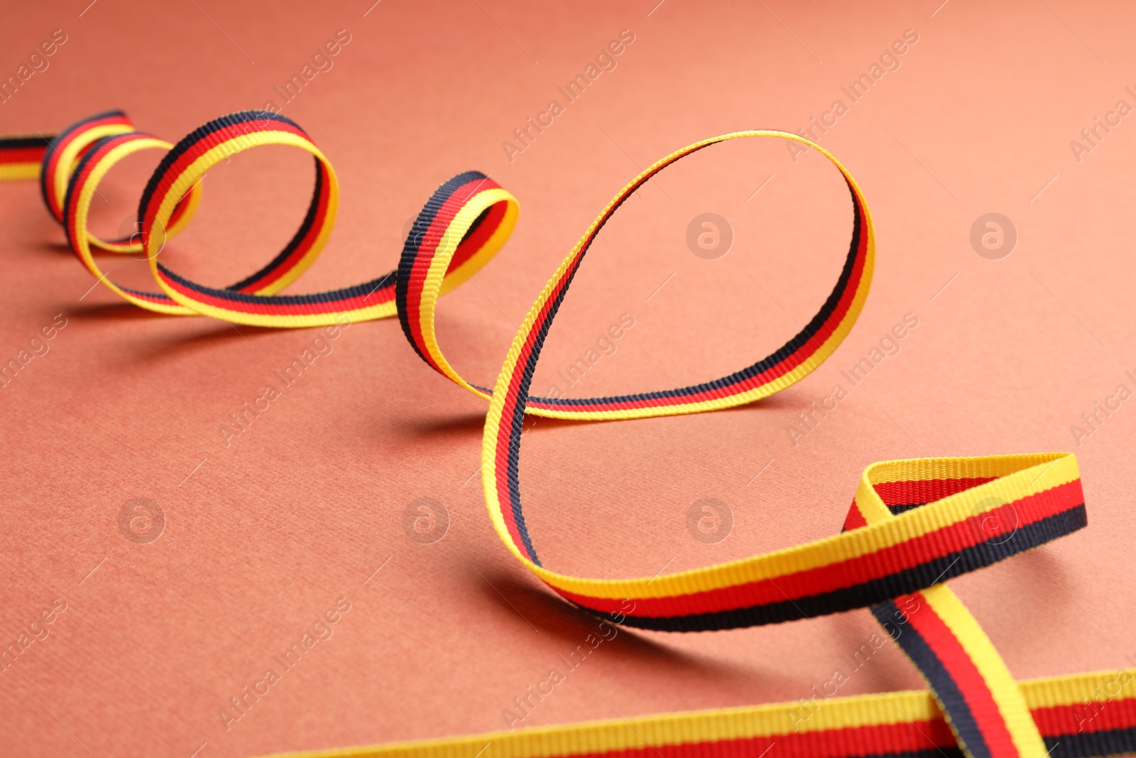 Photo of Ribbon in colors of German flag on color background, closeup