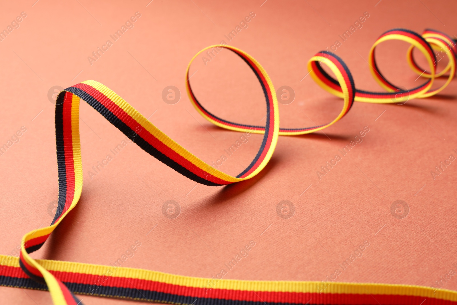 Photo of Ribbon in colors of German flag on color background, closeup