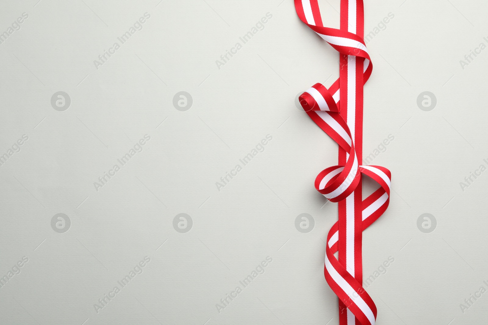 Photo of Ribbon in colors of Austrian flag on light background, top view. Space for text