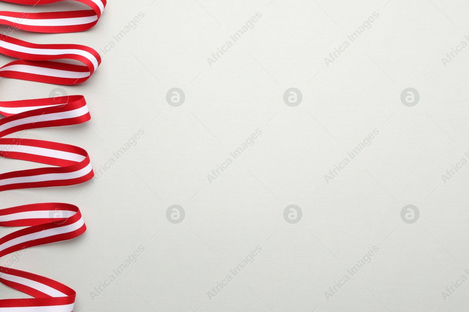 Photo of Ribbon in colors of Austrian flag on light background, top view. Space for text