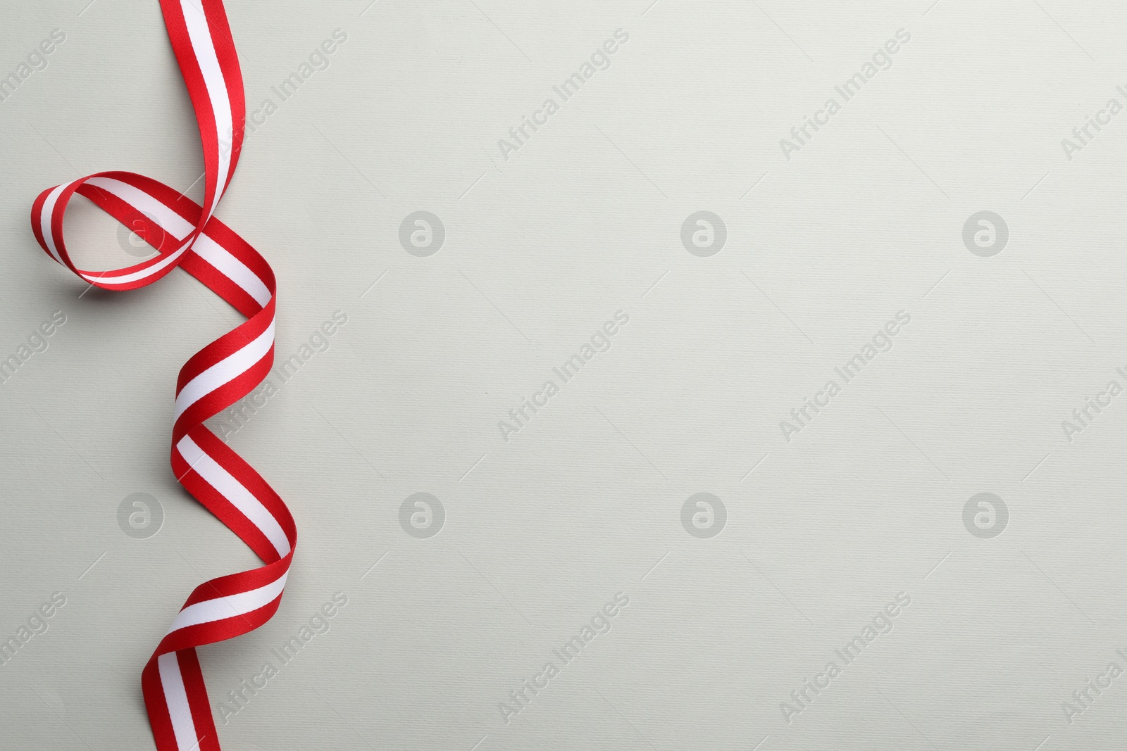 Photo of Ribbon in colors of Austrian flag on light background, top view. Space for text