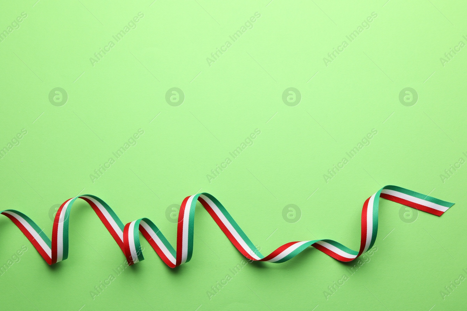 Photo of Ribbon in colors of Hungarian flag on green background, top view. Space for text