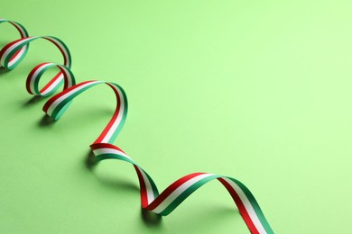 Photo of Ribbon in colors of Hungarian flag on green background. Space for text