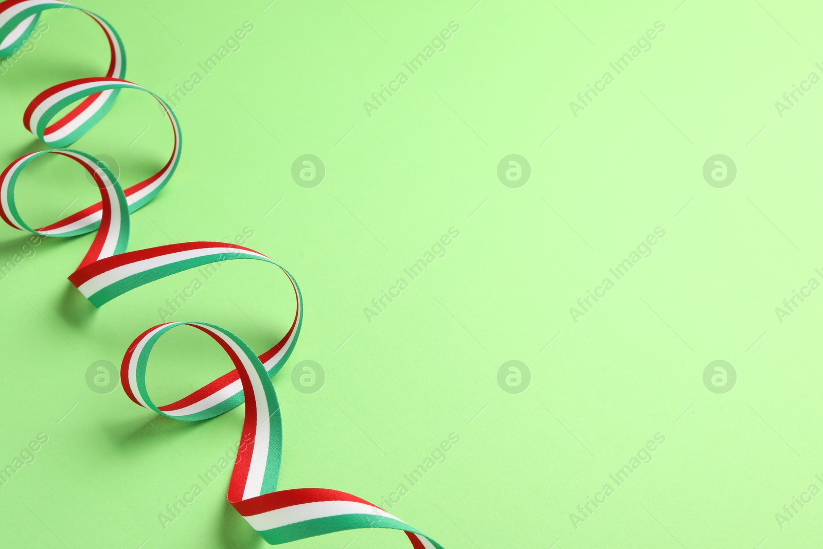 Photo of Ribbon in colors of Hungarian flag on green background. Space for text