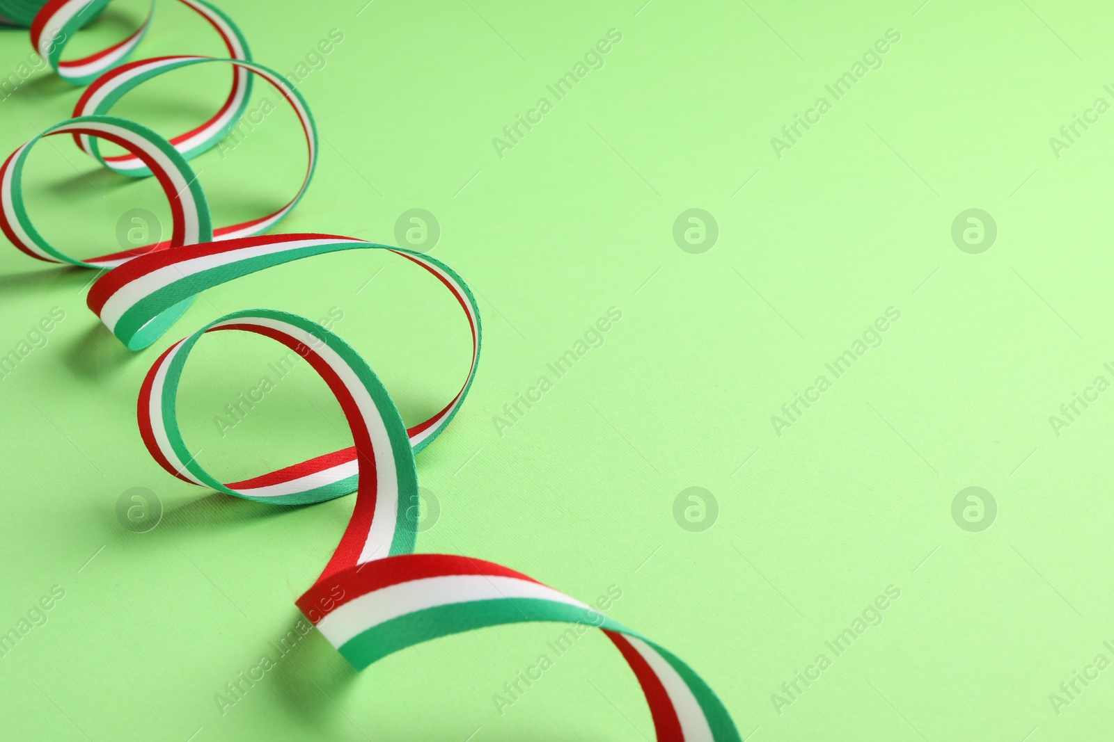 Photo of Ribbon in colors of Hungarian flag on green background. Space for text