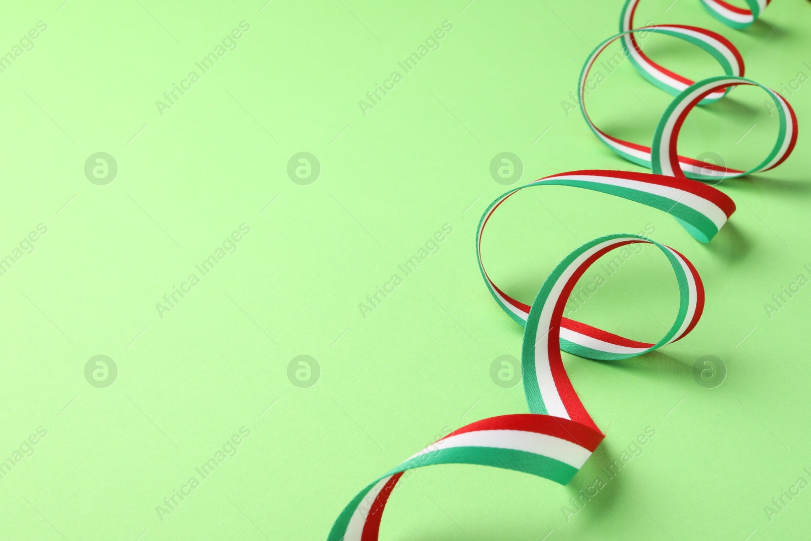 Photo of Ribbon in colors of Hungarian flag on green background. Space for text