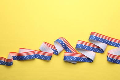 Photo of Ribbon in colors of USA flag on yellow background, top view