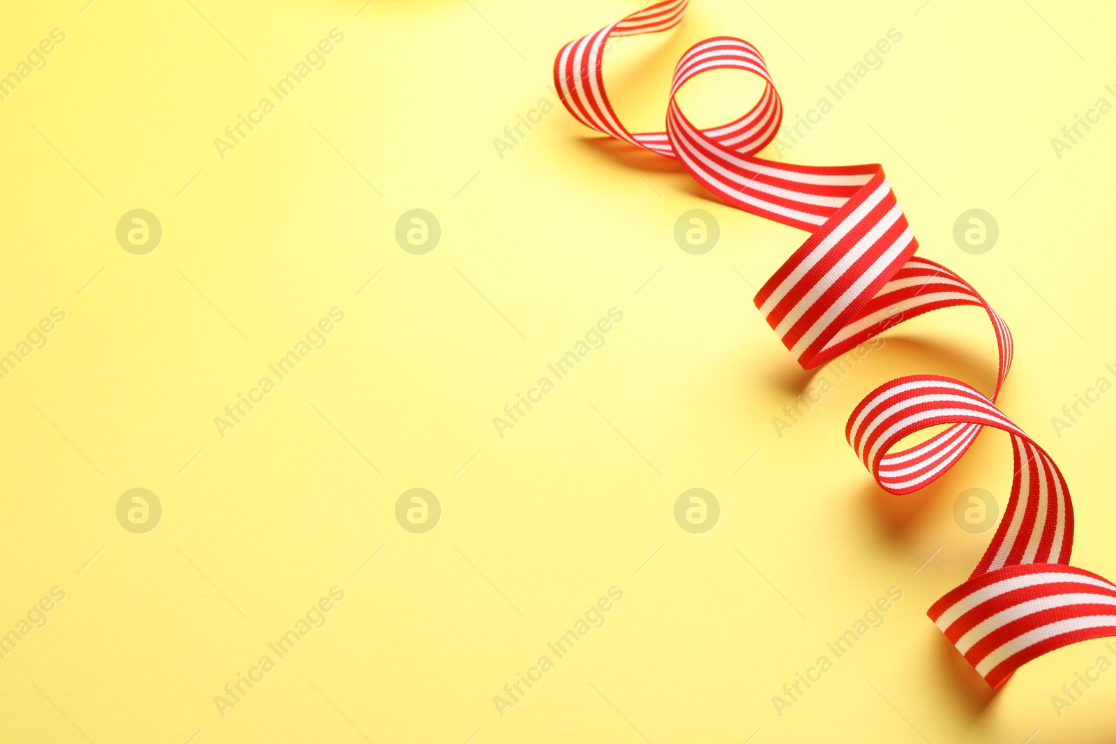 Photo of Striped ribbon on yellow background. Space for text