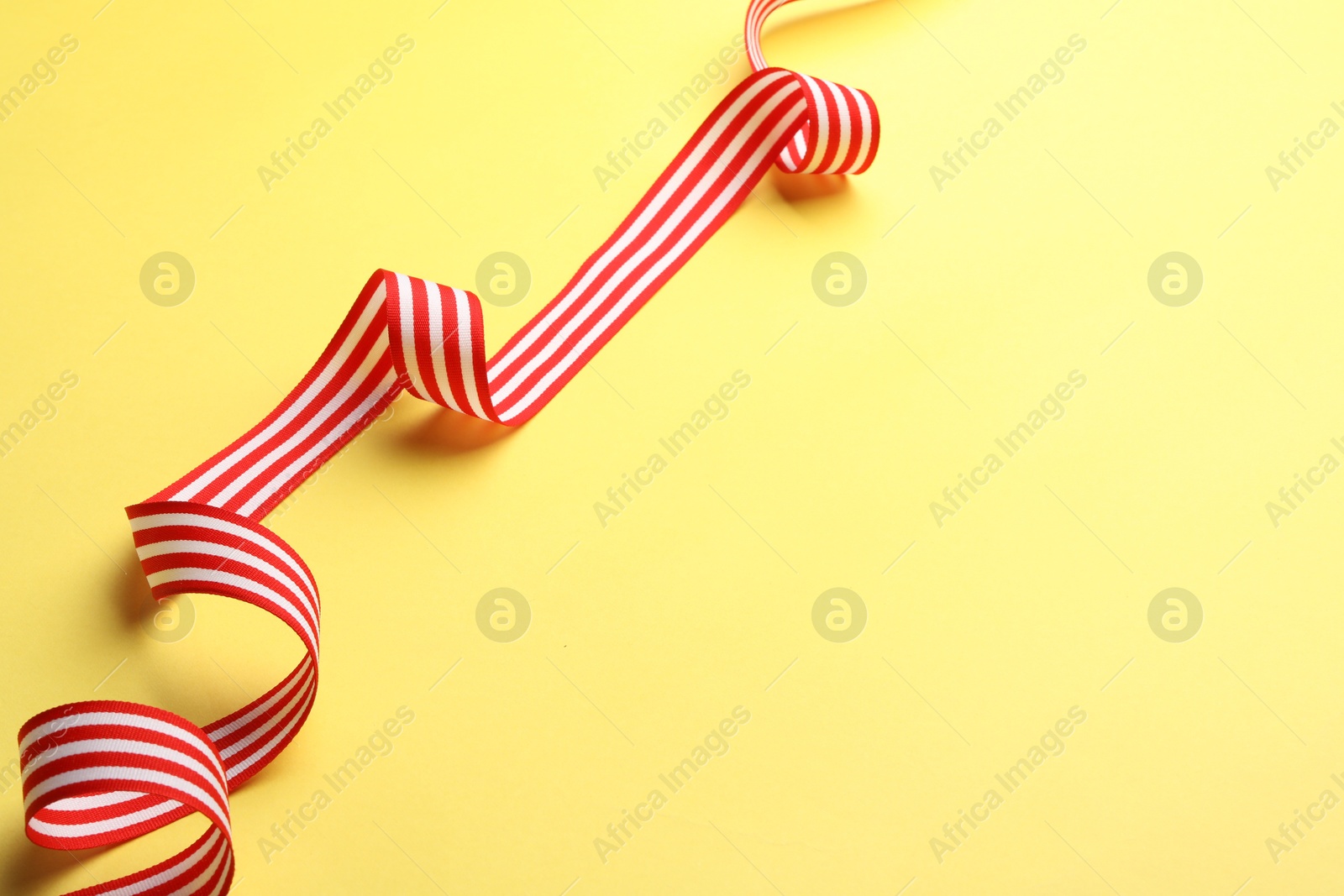 Photo of Striped ribbon on yellow background. Space for text