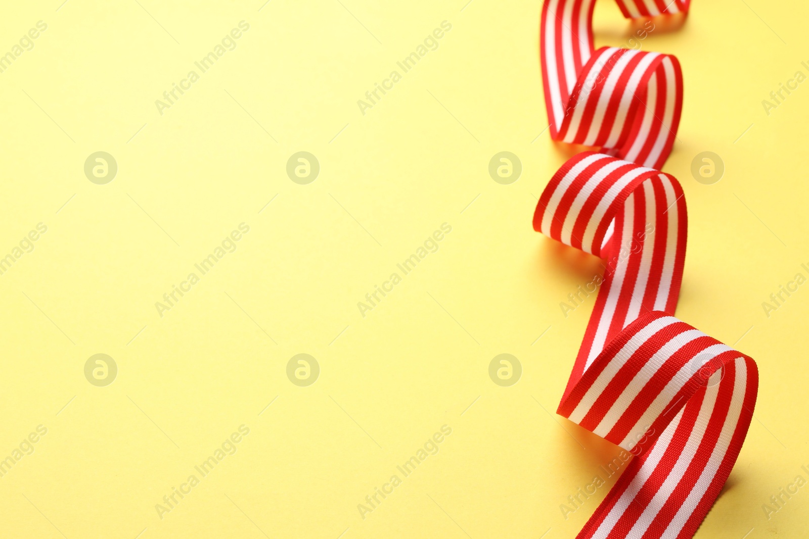 Photo of Striped ribbon on yellow background. Space for text