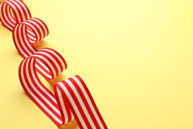 Striped ribbon on yellow background, closeup. Space for text