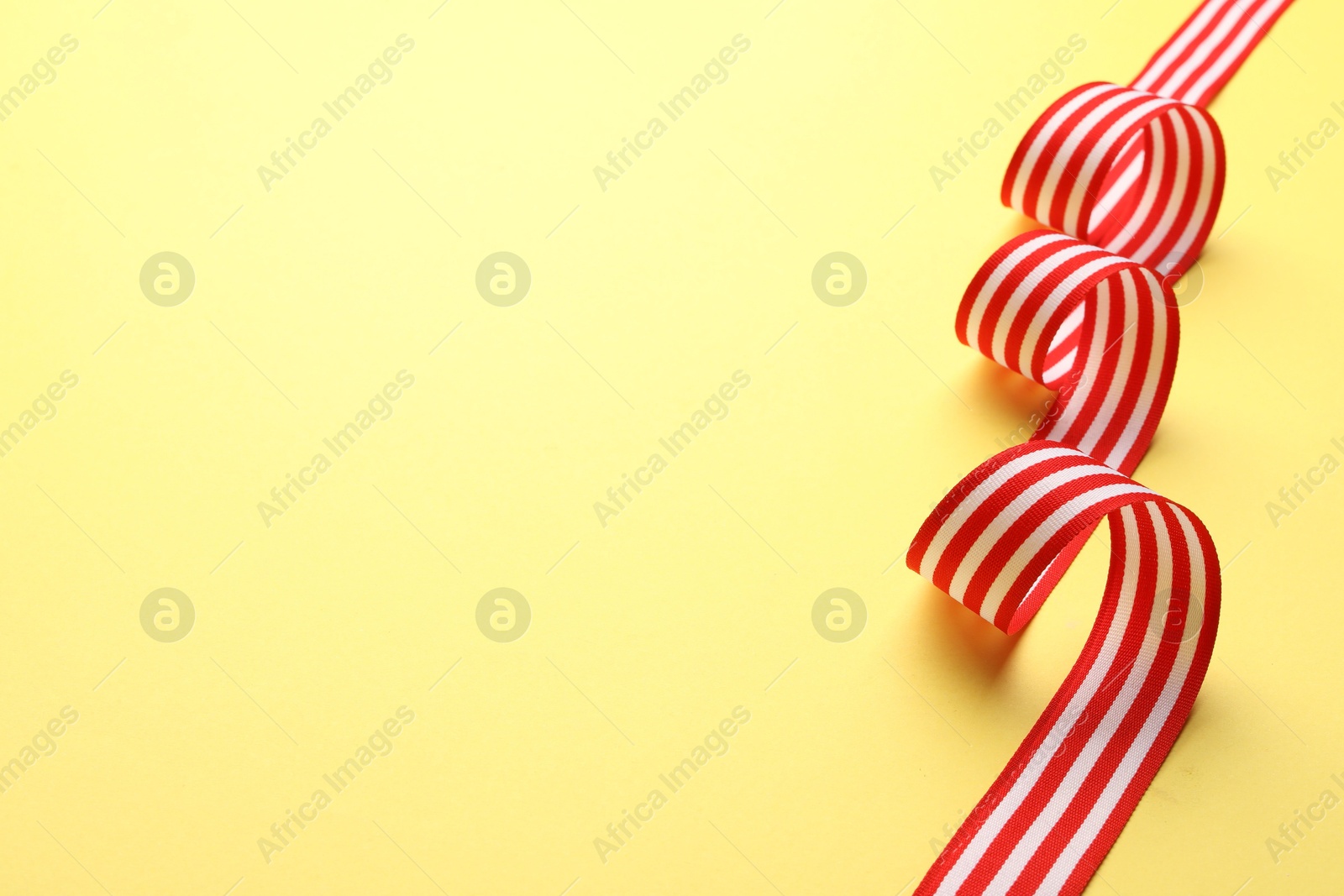 Photo of Striped ribbon on yellow background. Space for text