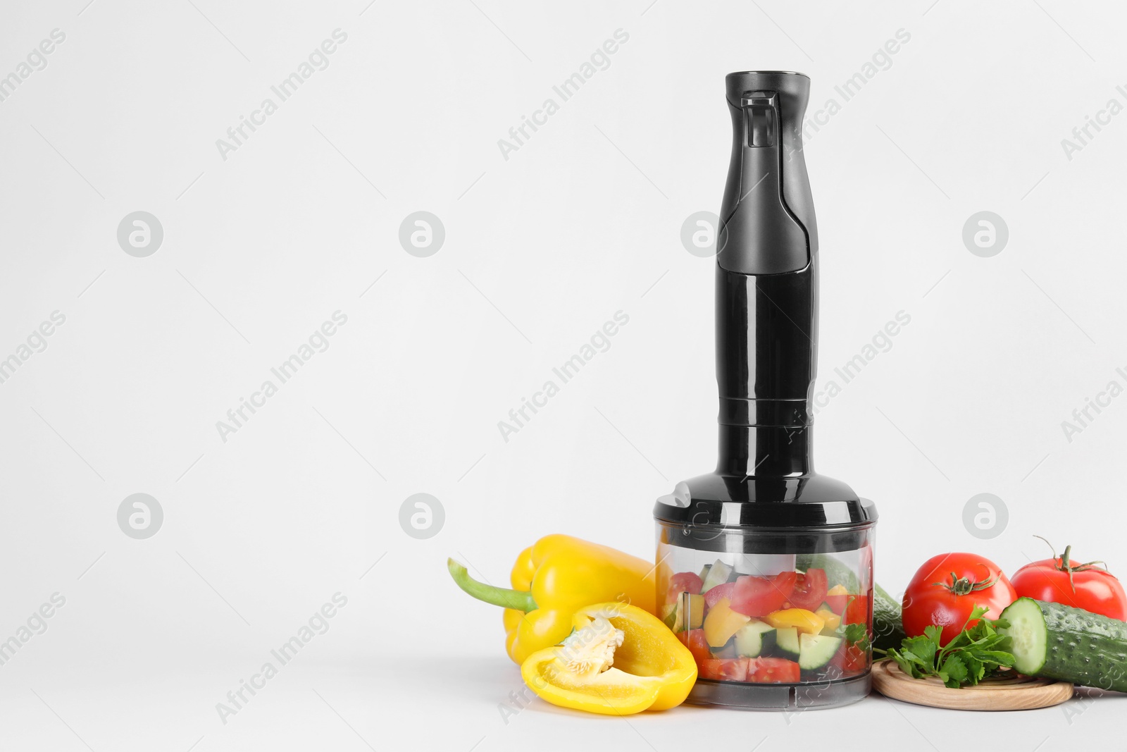 Photo of Hand blender kit, fresh vegetables and parsley on white background, space for text