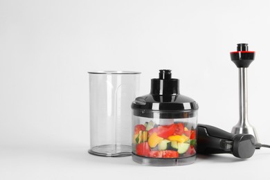 Hand blender kit with fresh vegetables on white background, space for text