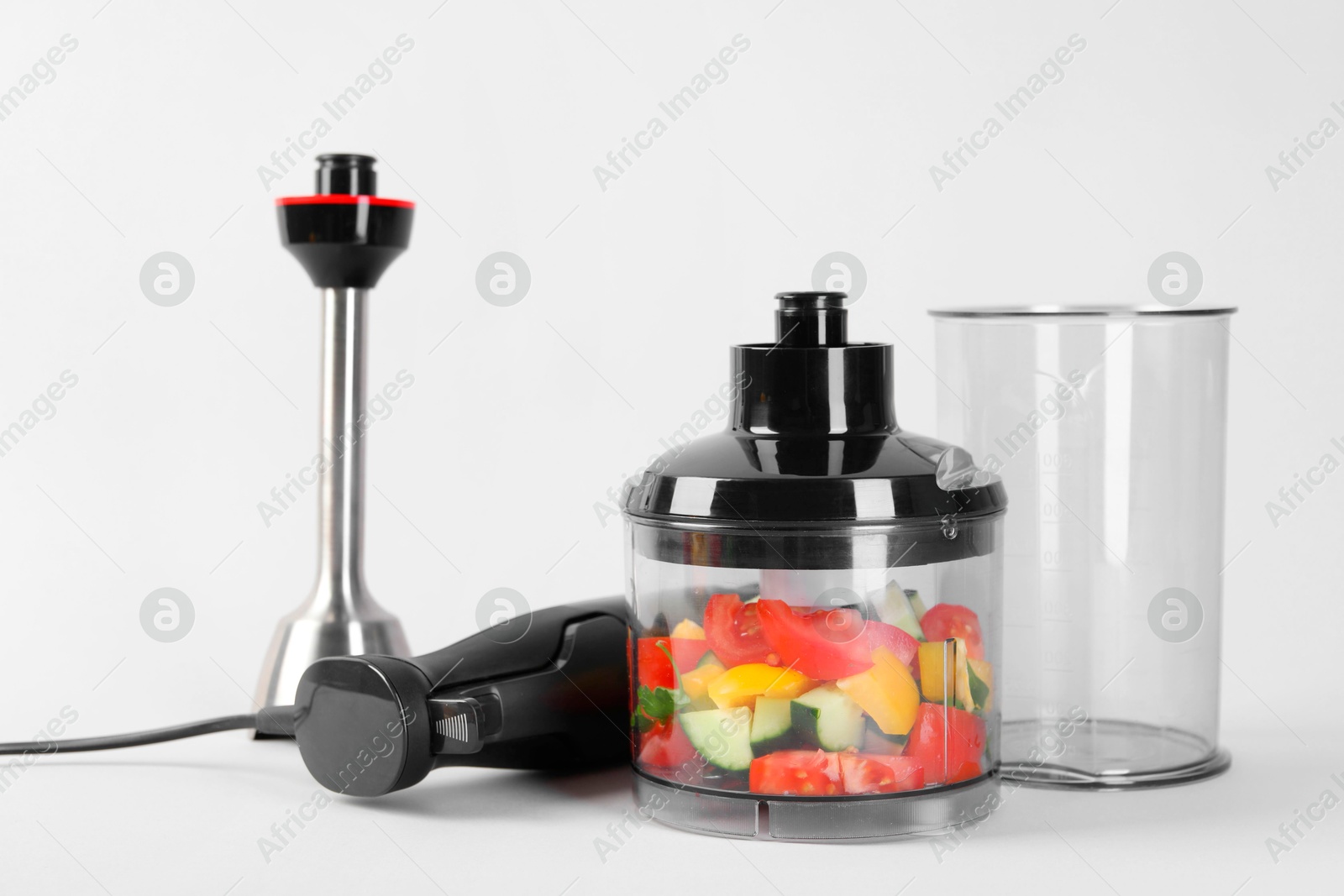 Photo of Hand blender kit with fresh vegetables on white background