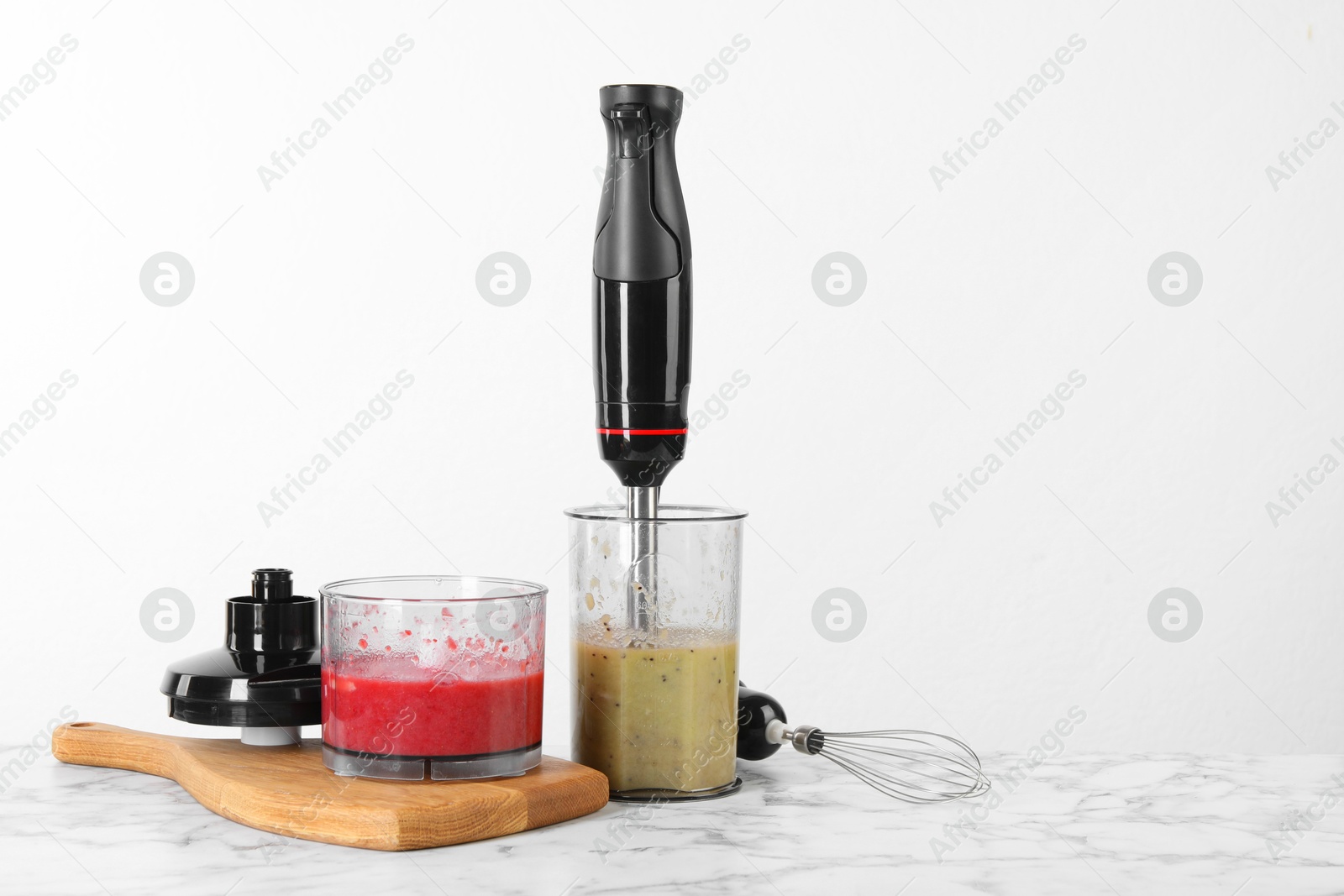 Photo of Hand blender kit and mixtures of ingredients on white marble table, space for text