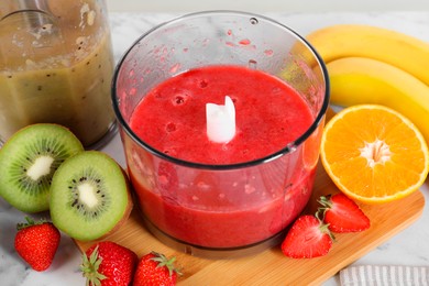 Photo of Hand blender kit, mixtures of ingredients and fresh fruits on table, closeup