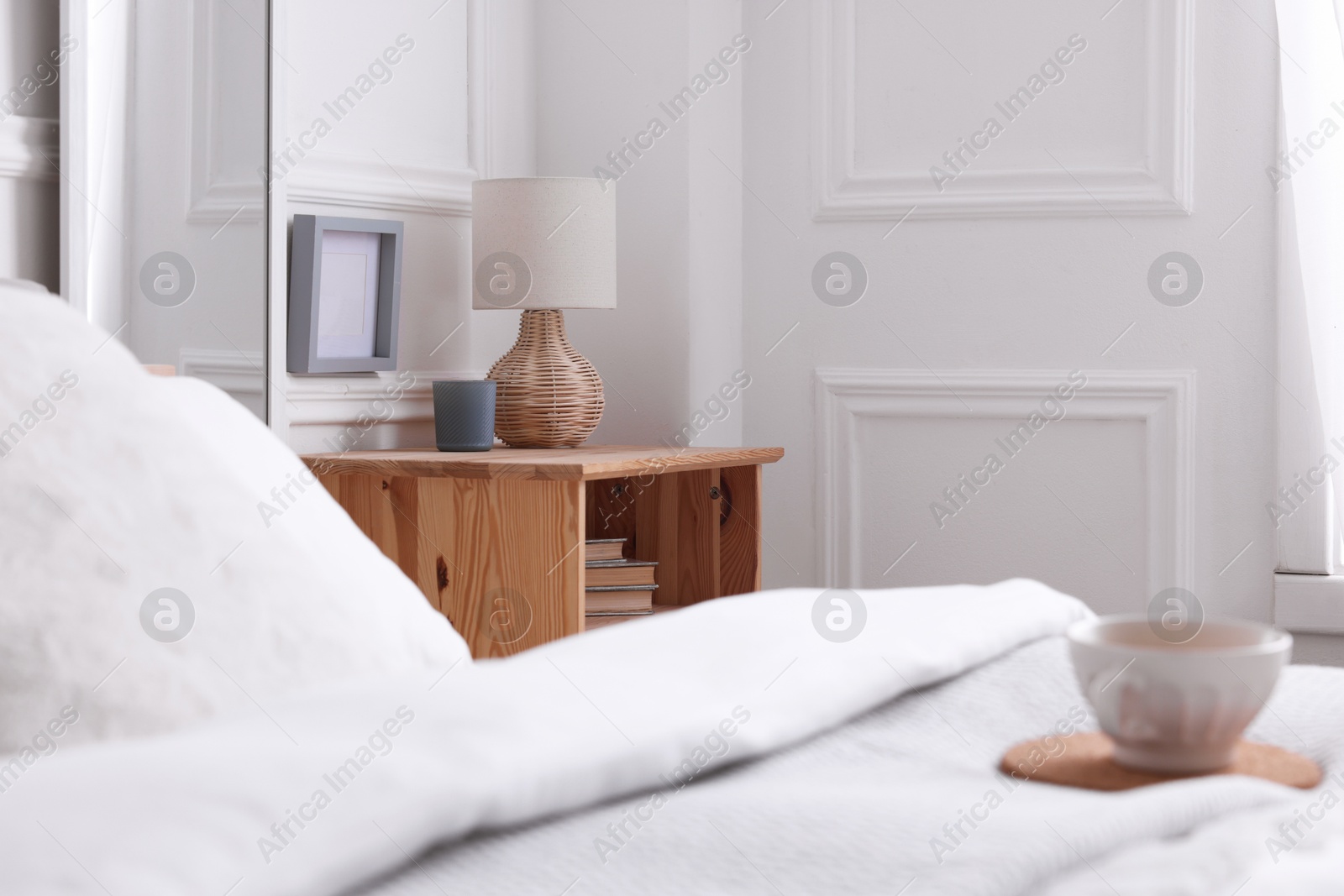 Photo of Stylish living room interior with bed, bedside table and lamp