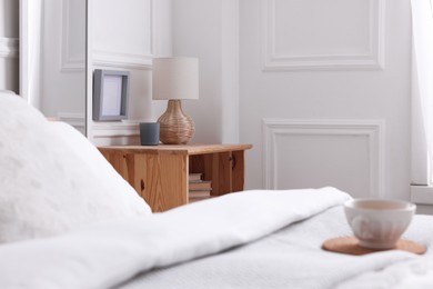 Photo of Stylish living room interior with bed, bedside table and lamp