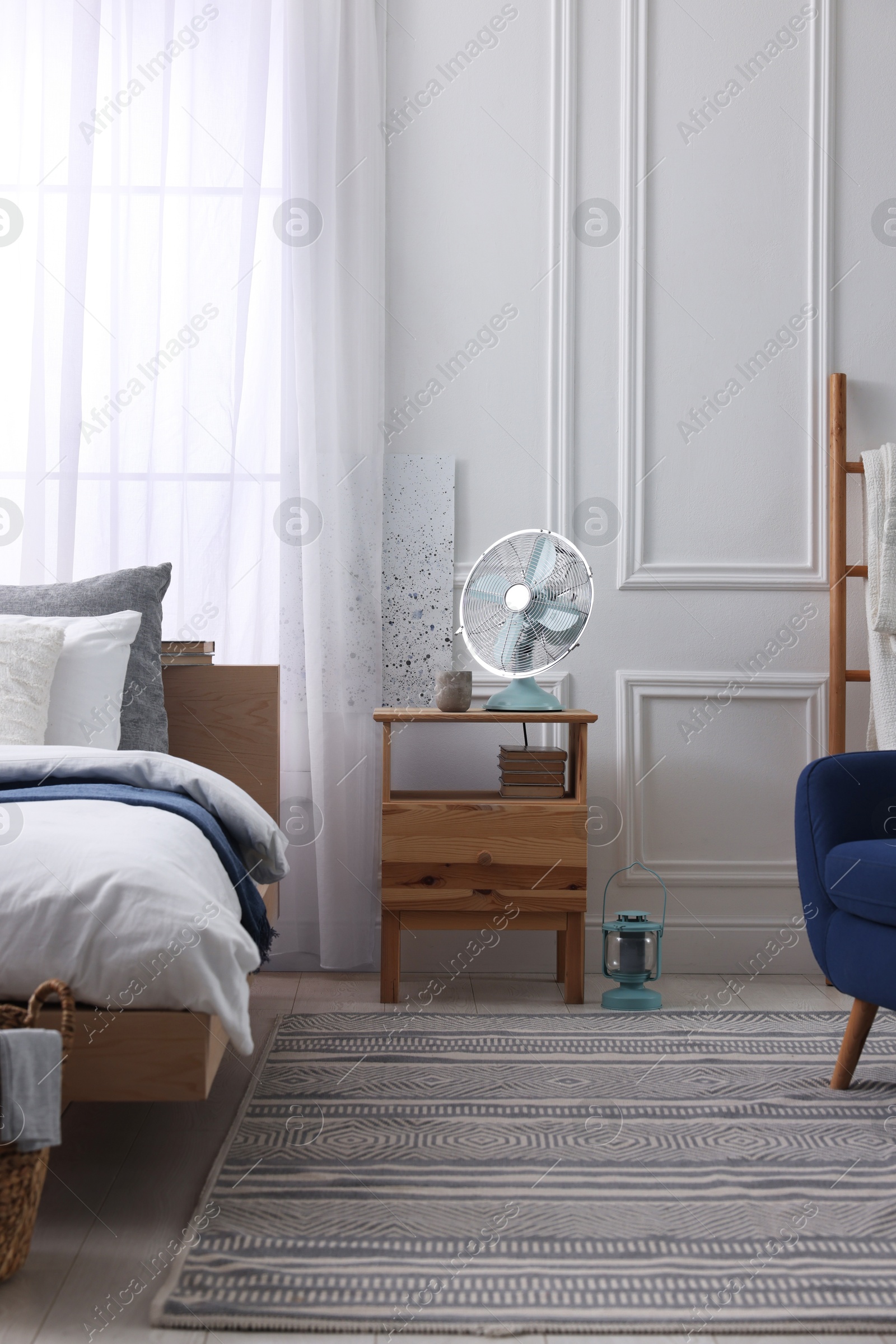 Photo of Stylish living room interior with bed, bedside table and fan