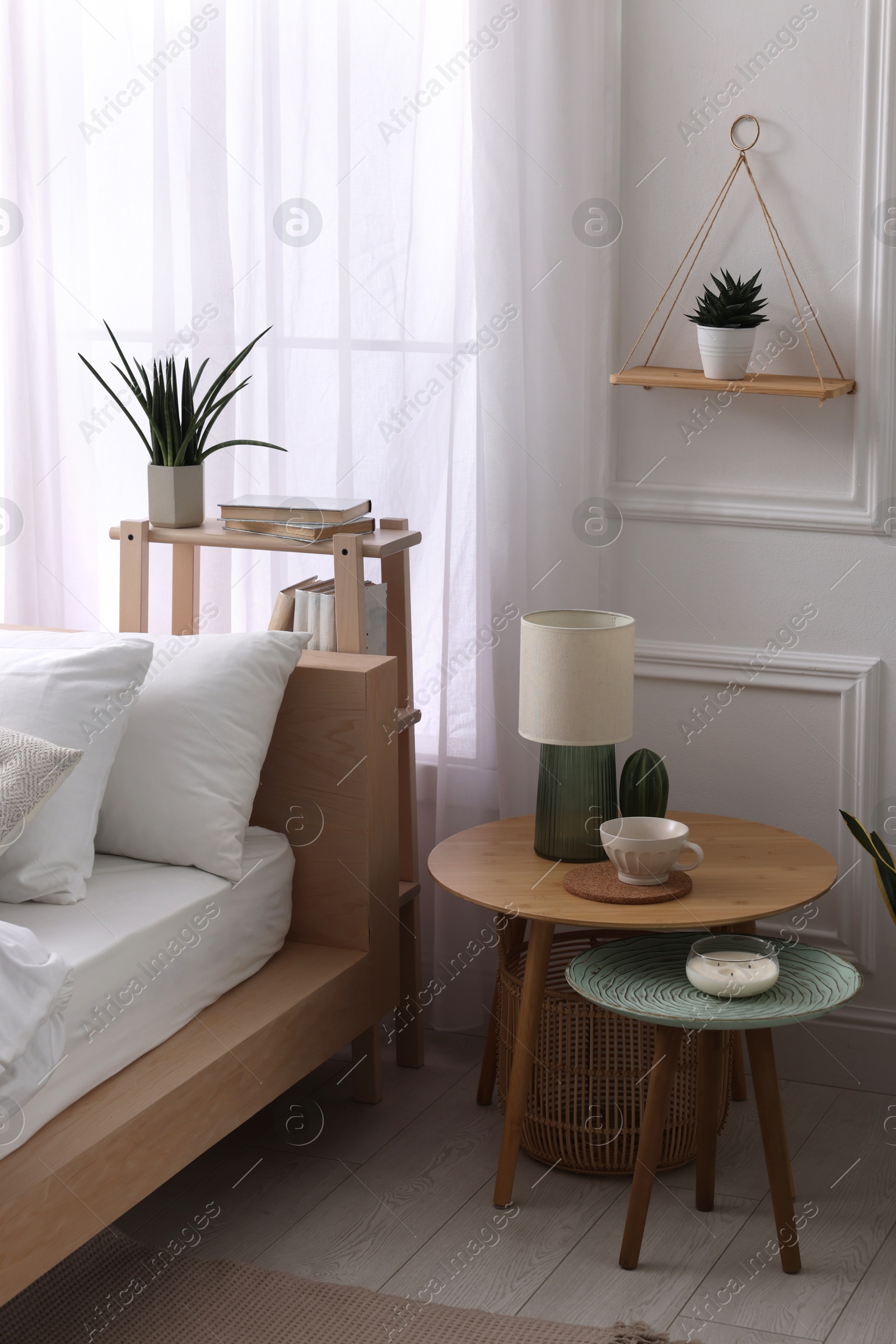 Photo of Stylish living room interior with bed, bedside tables, lamp and houseplants