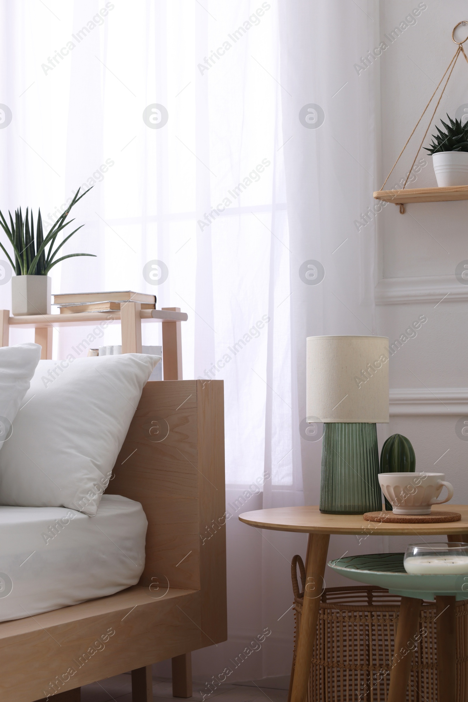 Photo of Stylish living room interior with bed, bedside tables, lamp and houseplants