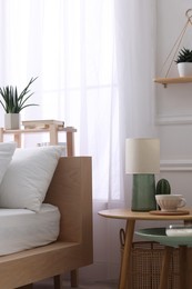 Photo of Stylish living room interior with bed, bedside tables, lamp and houseplants