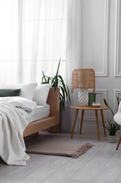 Photo of Stylish living room interior with bed, bedside table, lamp and houseplants