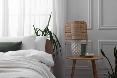 Photo of Stylish living room interior with bed, bedside table, lamp and houseplants