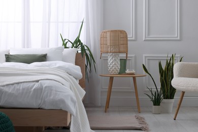 Photo of Stylish living room interior with bed, bedside table, lamp and houseplants