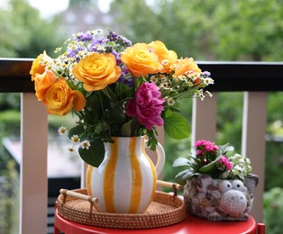 Photo of Vase with beautiful flowers on red table at balcony