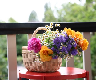 Wicker basket with beautiful flowers on red table at balcony