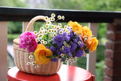 Wicker basket with beautiful flowers on red table at balcony