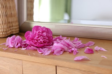 Photo of Beautiful pink peony and petals on wooden table indoors, closeup