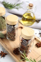 Photo of Glass jars with different spices on white marble table