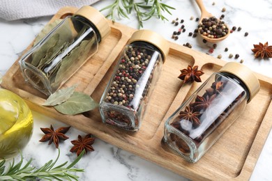 Photo of Glass jars with different spices on white marble table