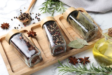 Glass jars with different spices on white marble table