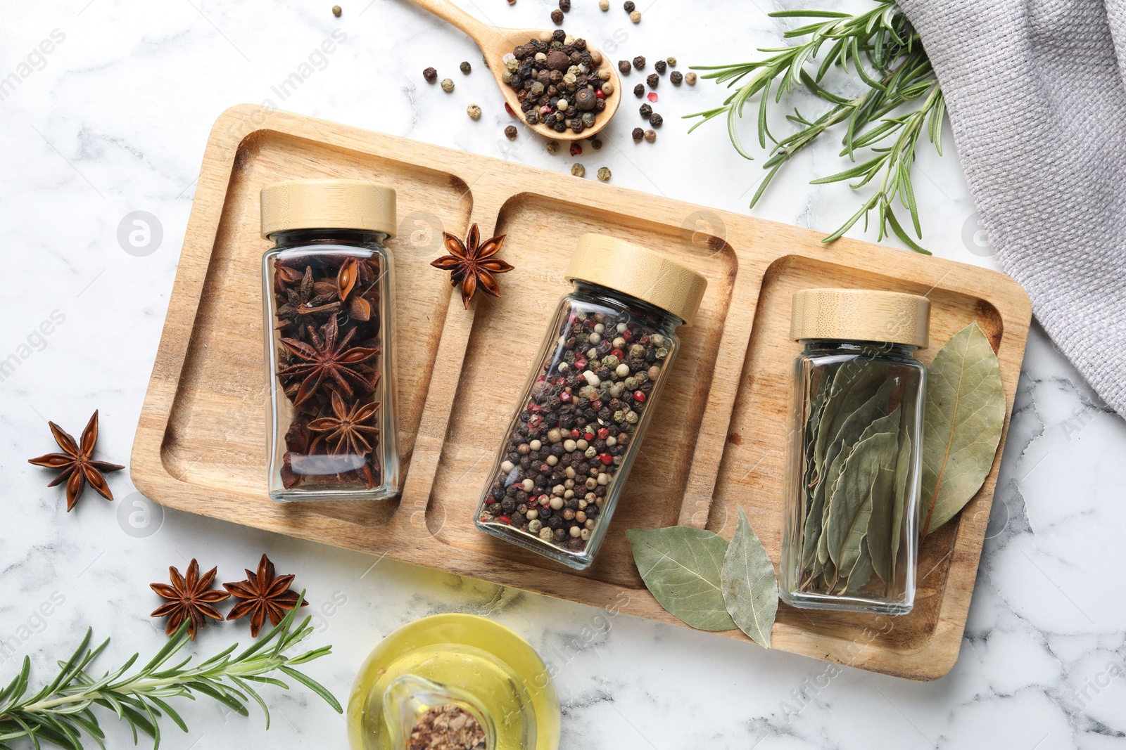 Photo of Glass jars with different spices on white marble table, flat lay