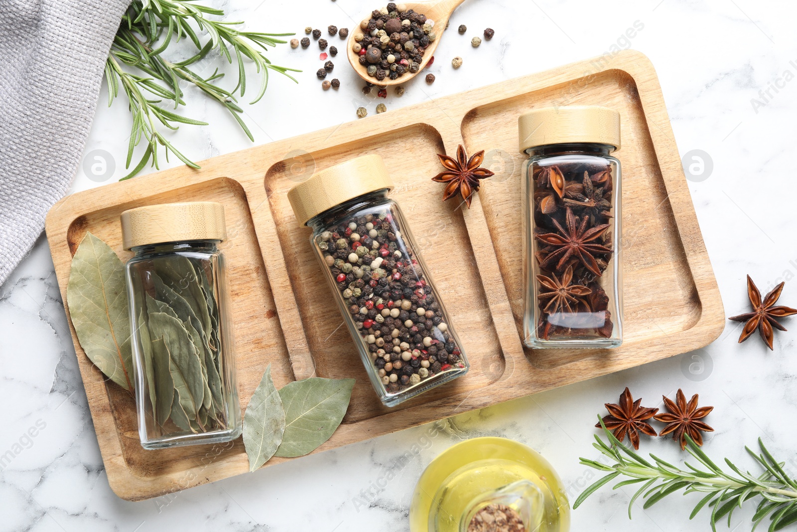 Photo of Glass jars with different spices on white marble table, flat lay