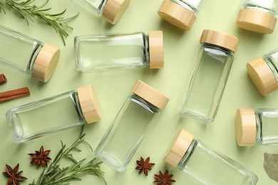 Photo of Different spices and glass jars on green background, flat lay