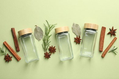 Different spices and glass jars on green background, flat lay